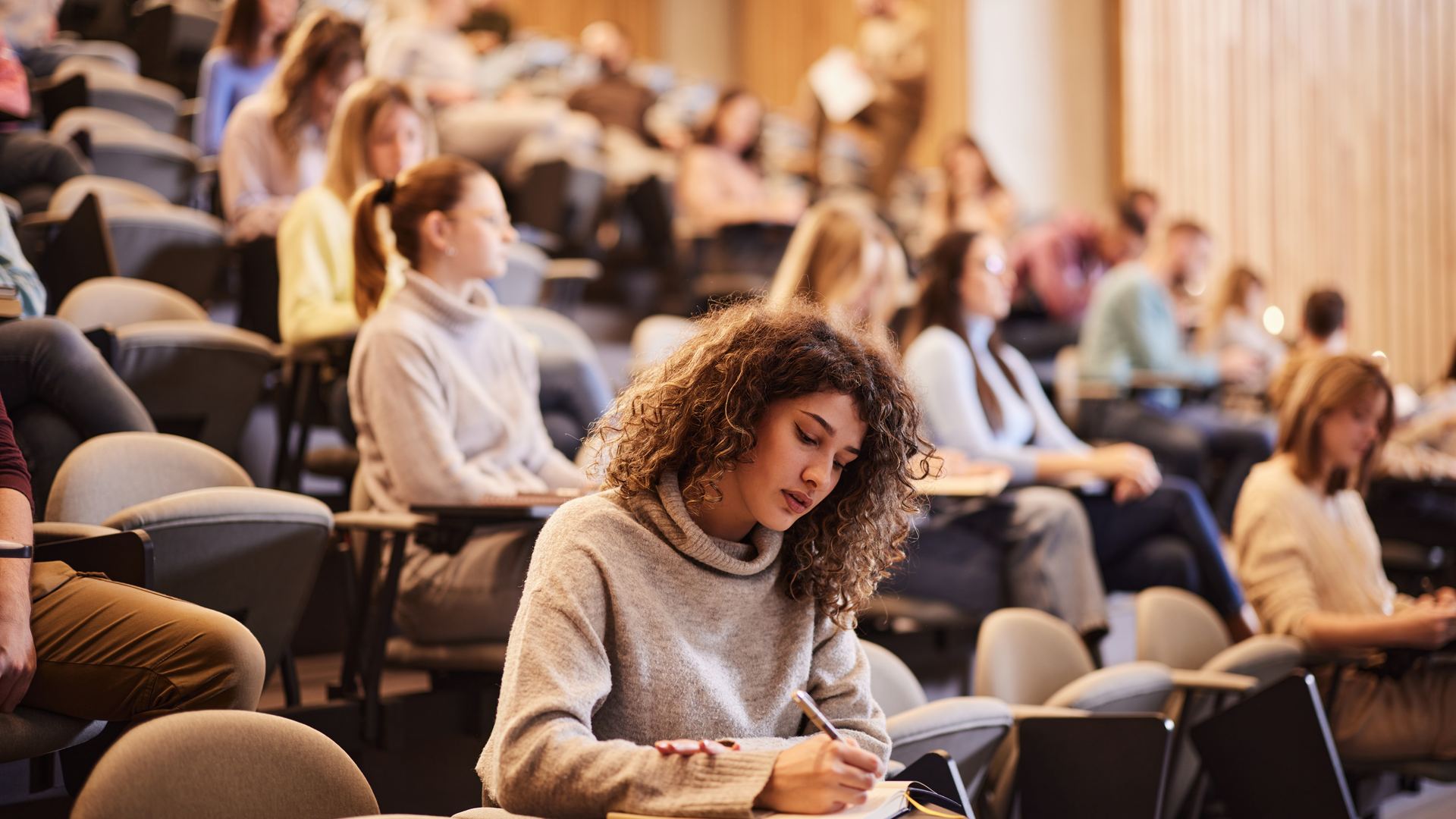 Students writing an exam in a university lecture theatre